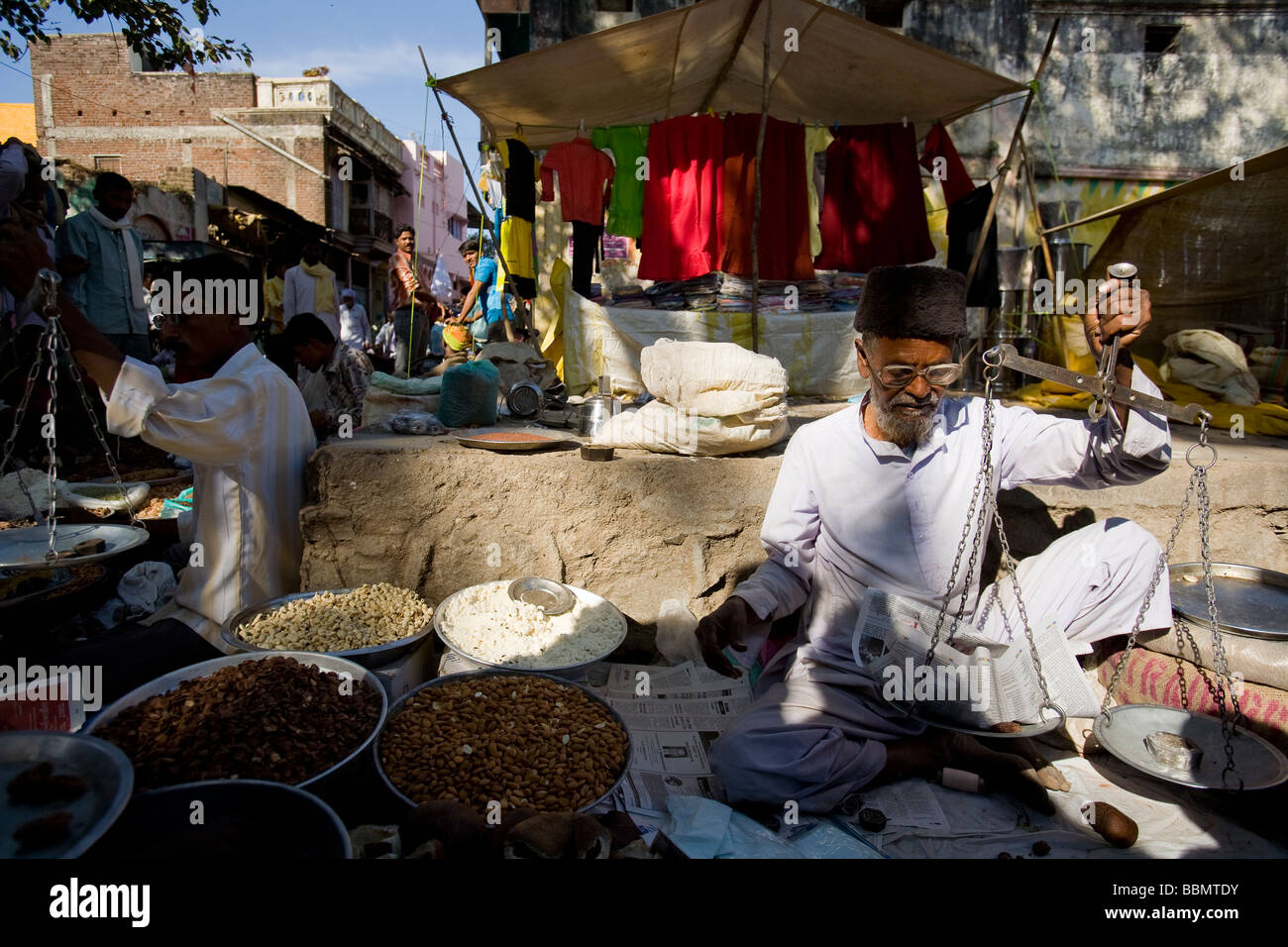 An Indian nut vendor weighs almonds for a customer at the Muslim market