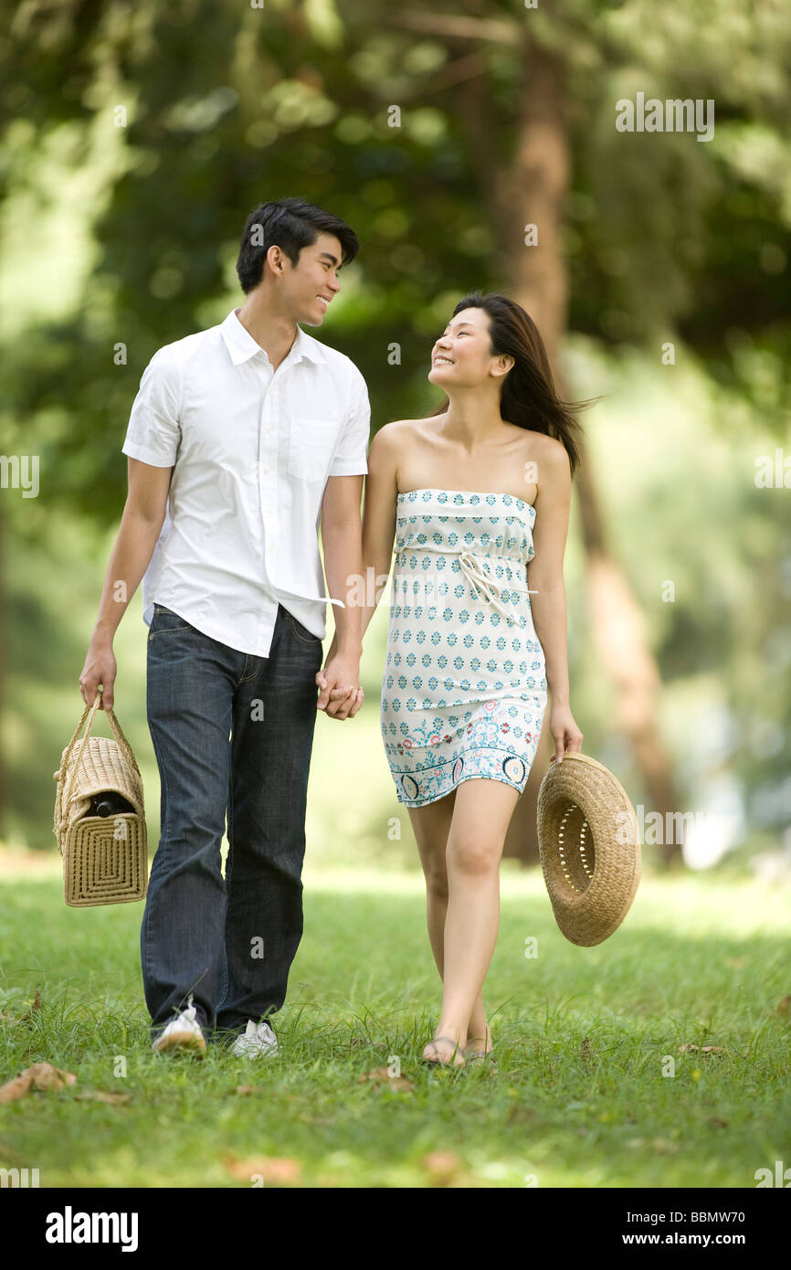 Young couple walking in the park holding hands Stock Photo - Alamy