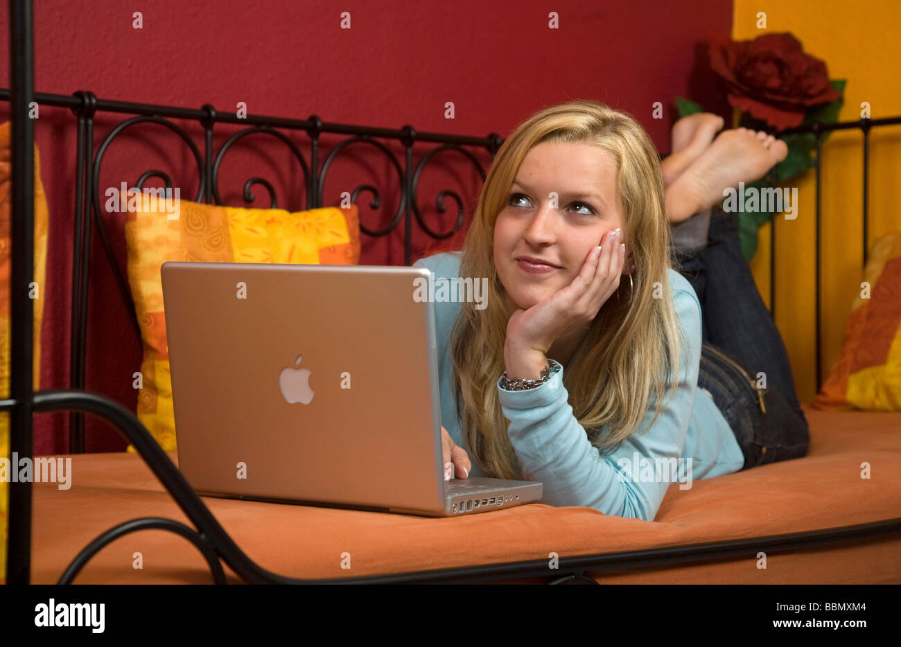 Young woman lying on a bed using a laptop Stock Photo