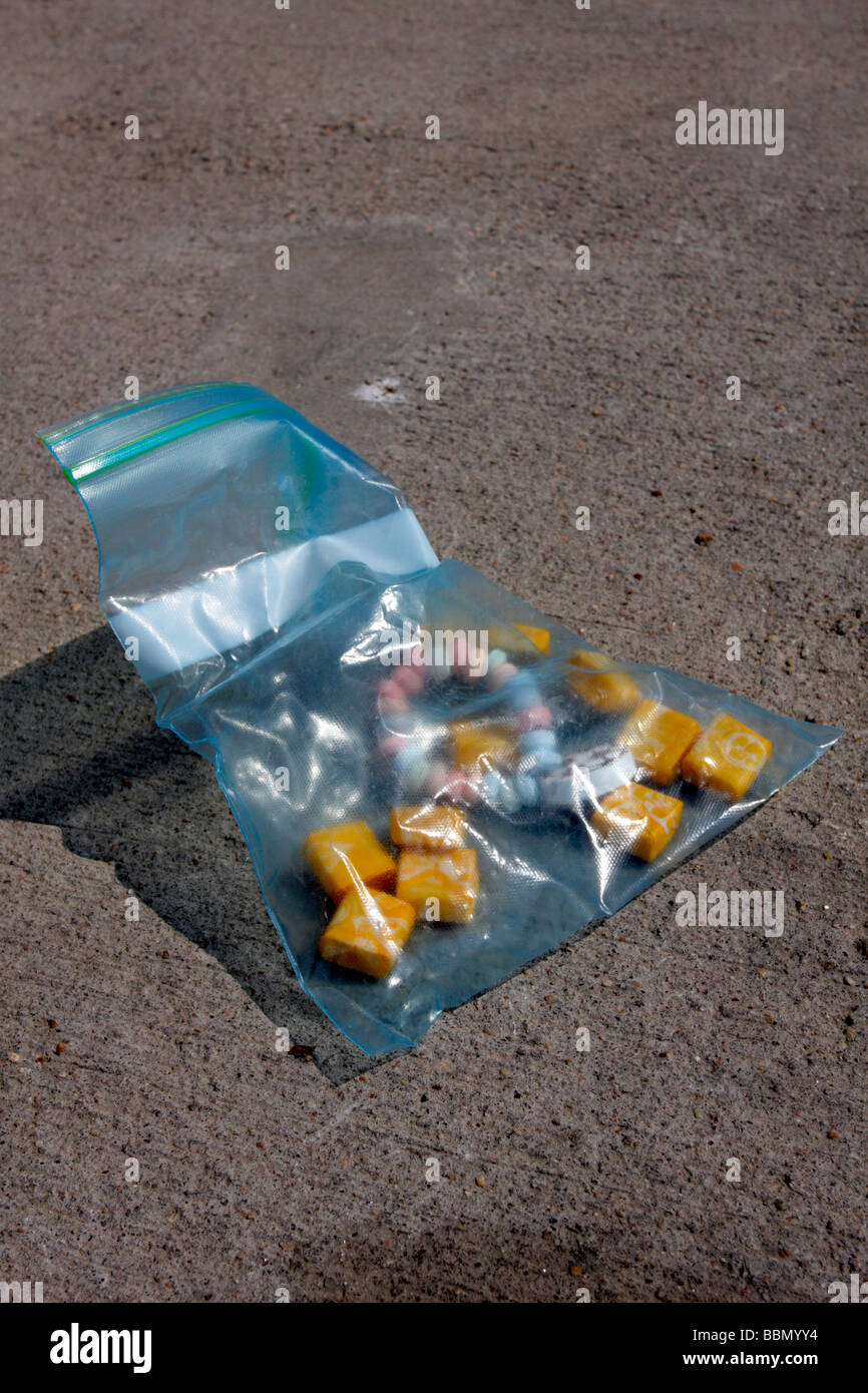 A partially filled ziploc baggie on concrete with candy and starburst fruit chews. Stock Photo