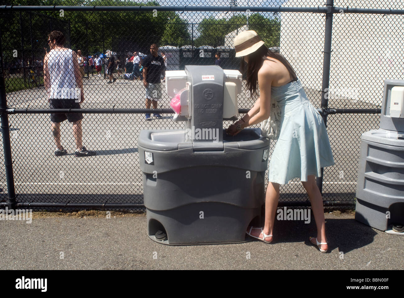 A woman washes her hands at an portable outdoor hand washing station in
