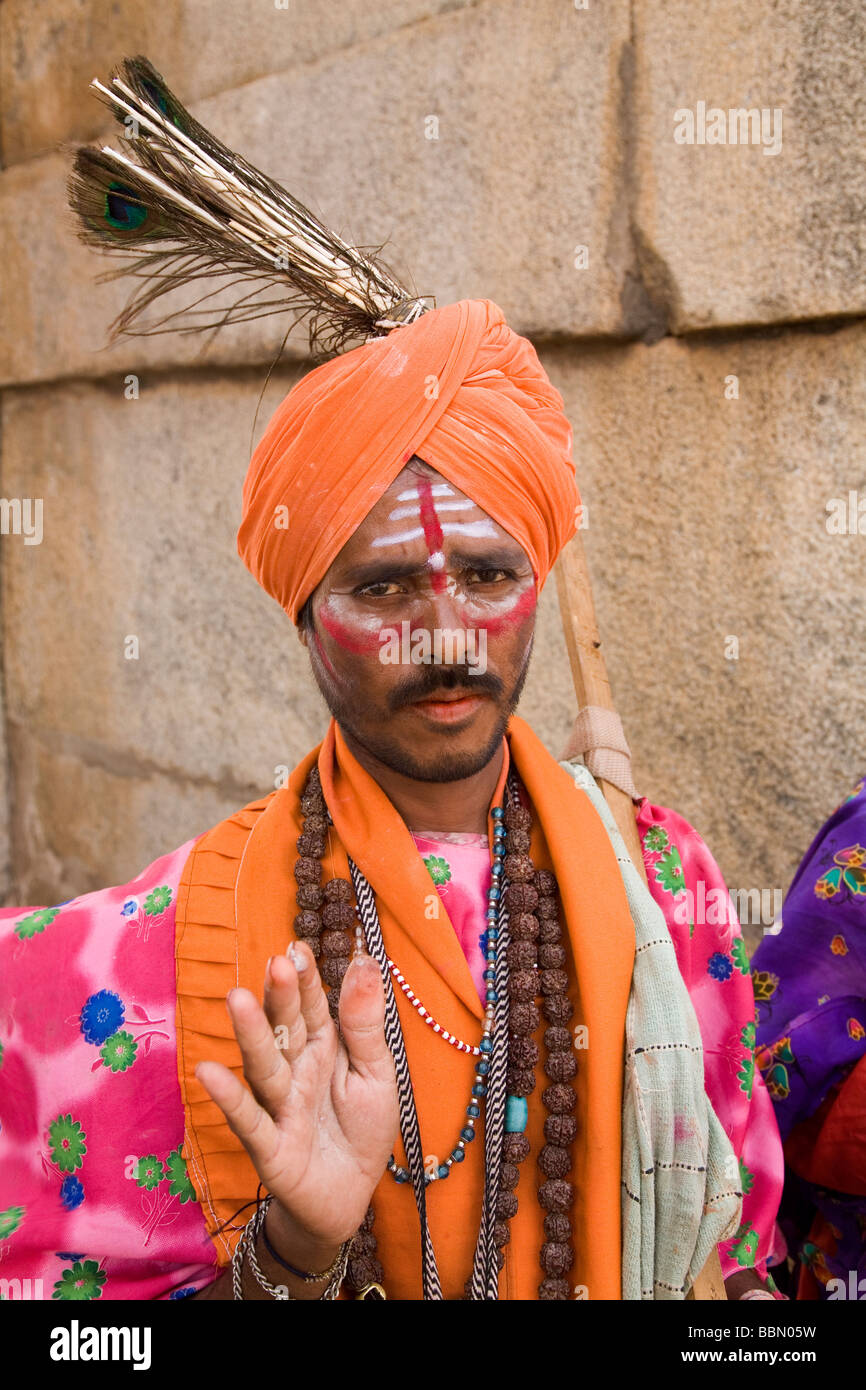 A turban clad sadhu (sanyasi) in Hampi, India. The man wears brightly coloured clothes and lives from donations. Stock Photo