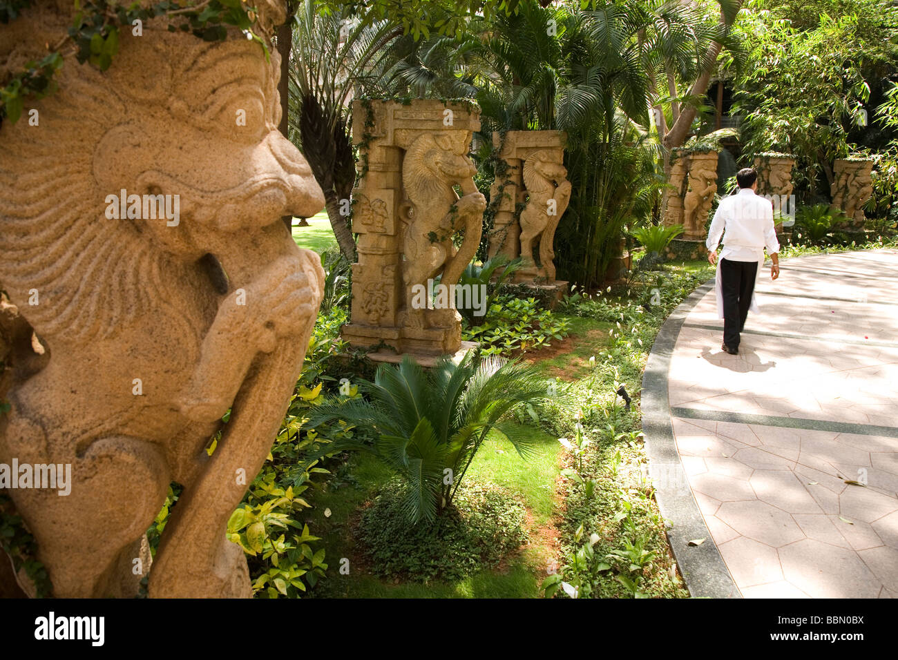 Carved stone figures in Karnataka in southern India. A man walks by the figures. Stock Photo