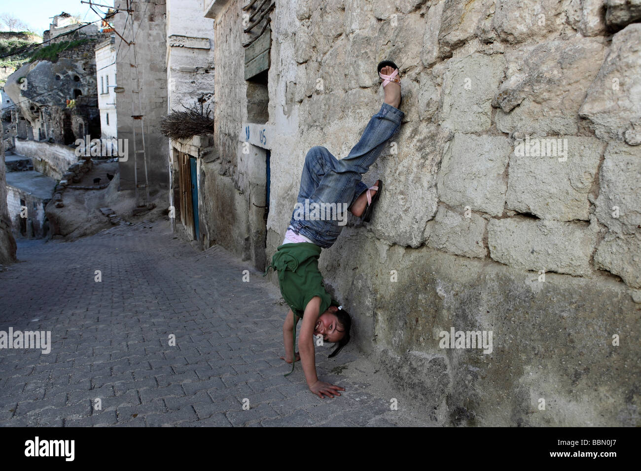 Teenager contorts herself with a funny pose in a remote village. Stock Photo