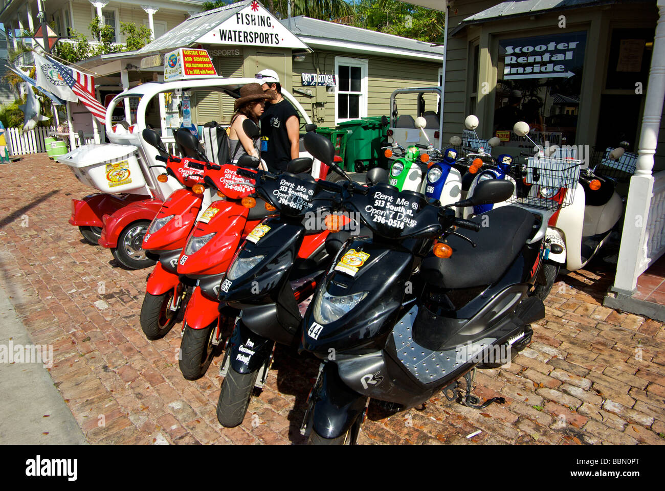 Tourist couple looking over bright scooters to rent at rental for touring Key West Stock - Alamy