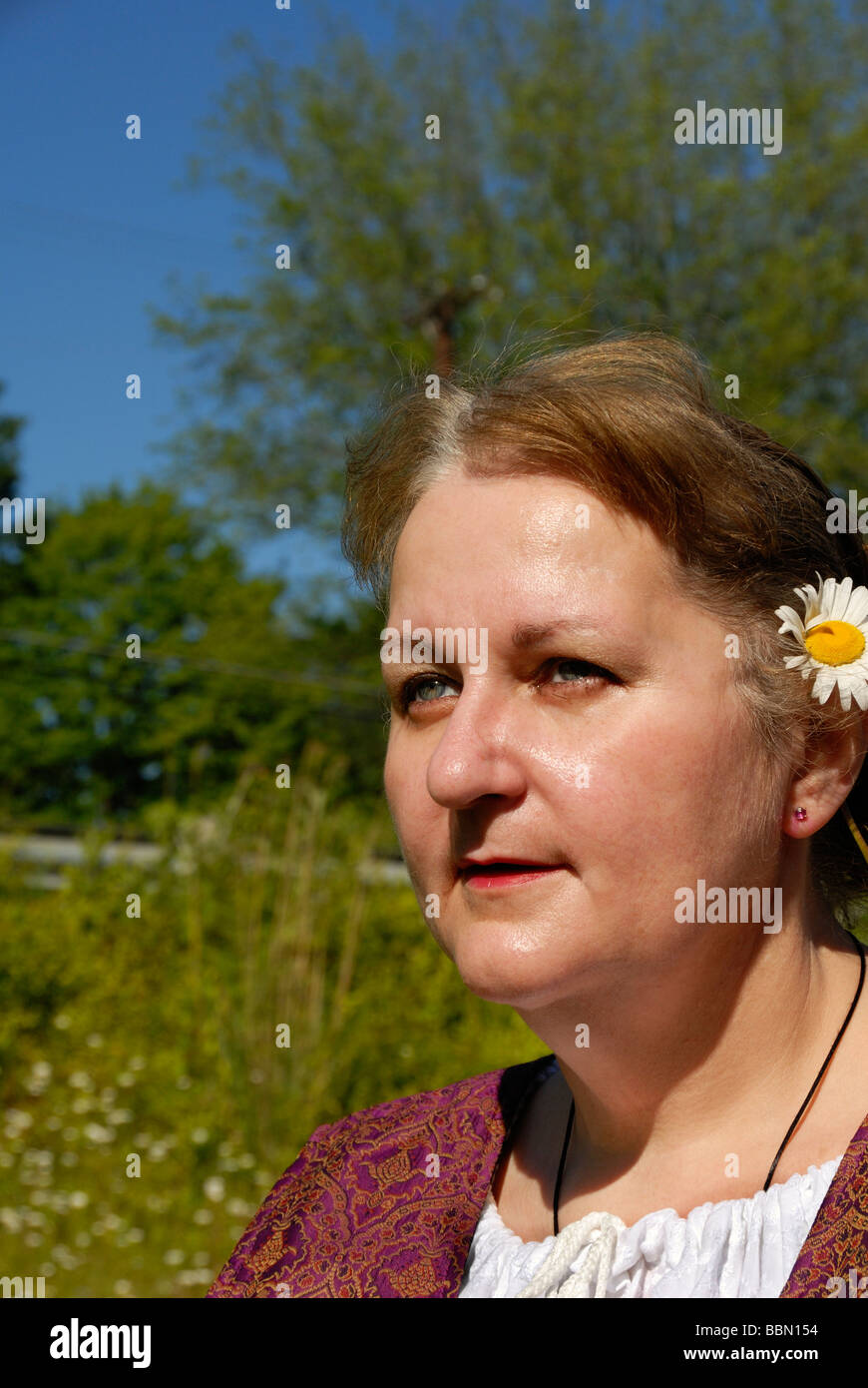 woman in field with flower in her hair Stock Photo