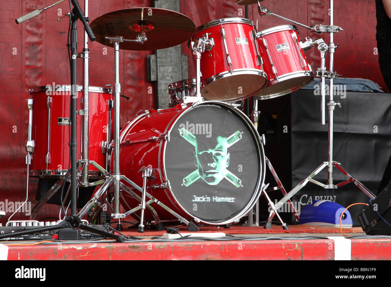 Red drum kit with a skull and crossbones type face painted on the bass drum Stock Photo