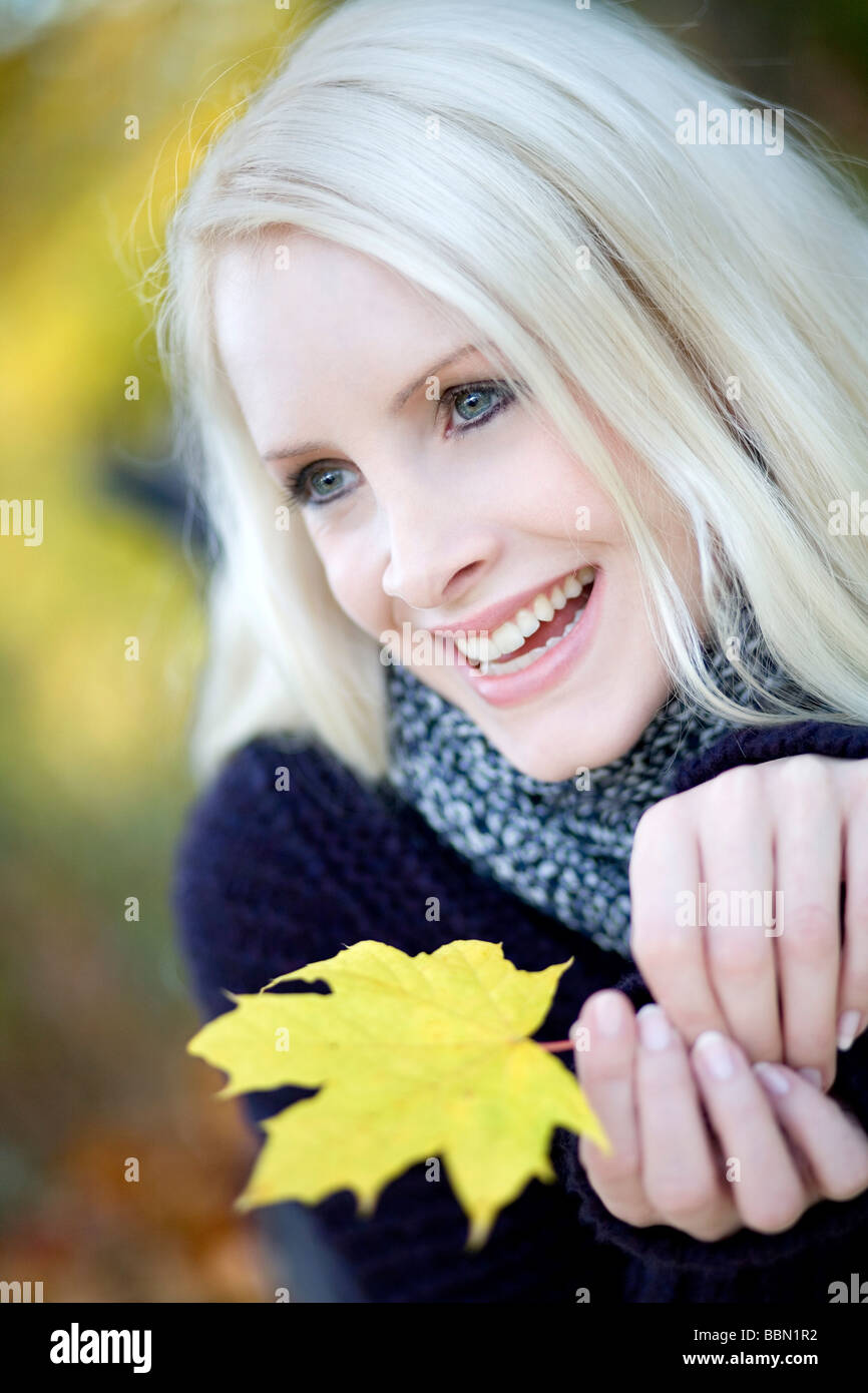 Young woman holding maple leaf, laughing, portrait Stock Photo - Alamy