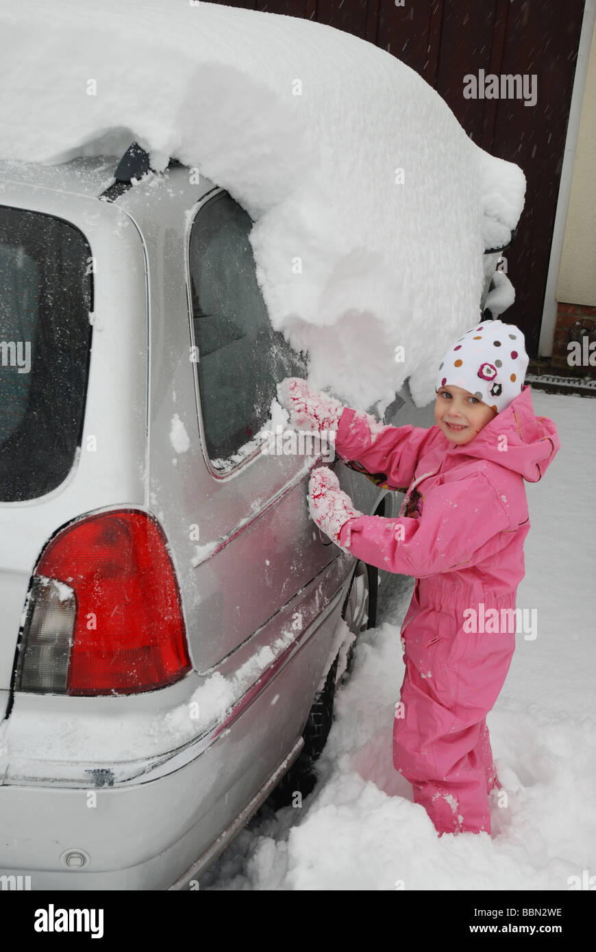 Child in pink snowsuit clearing heavy snow Stock Photo Alamy