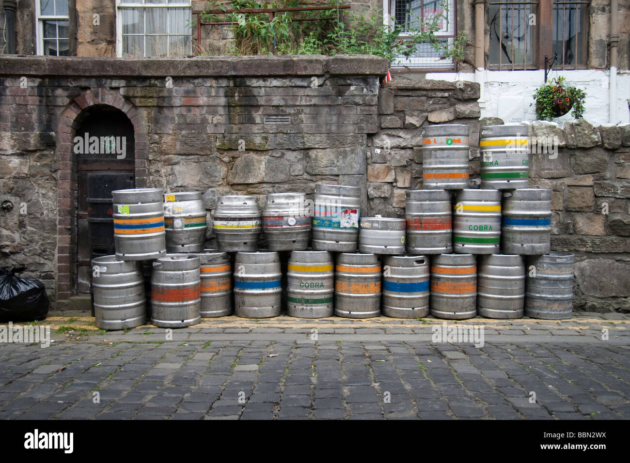 Beer kegs stacked against an old wall on a cobbled street Stock Photo