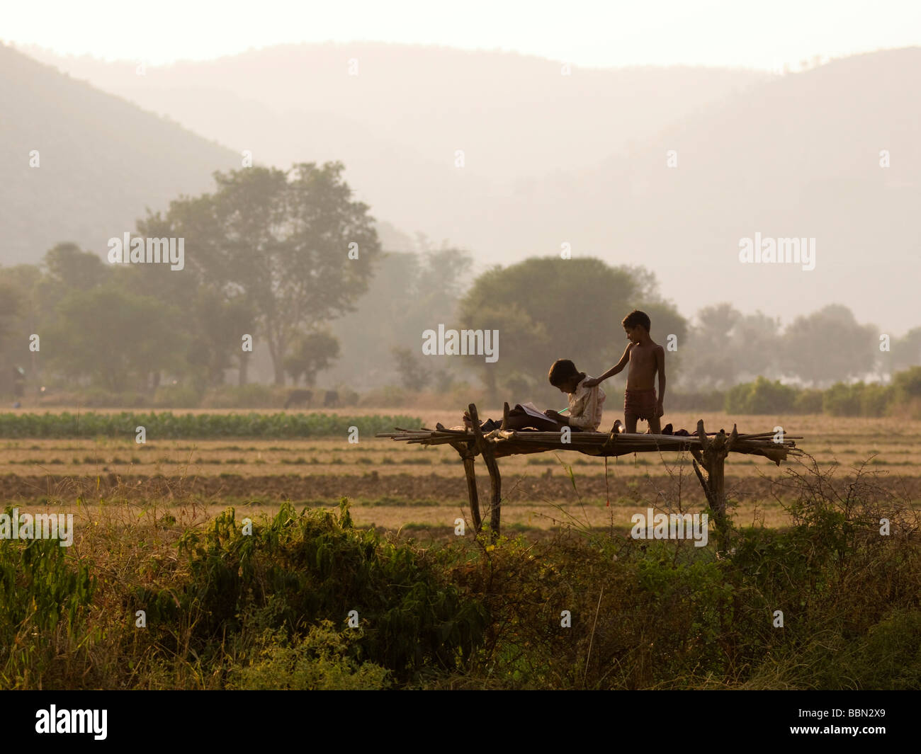 Rajasthan,India;Two boys on a raised wooden platform in Aravalli Hills Stock Photo