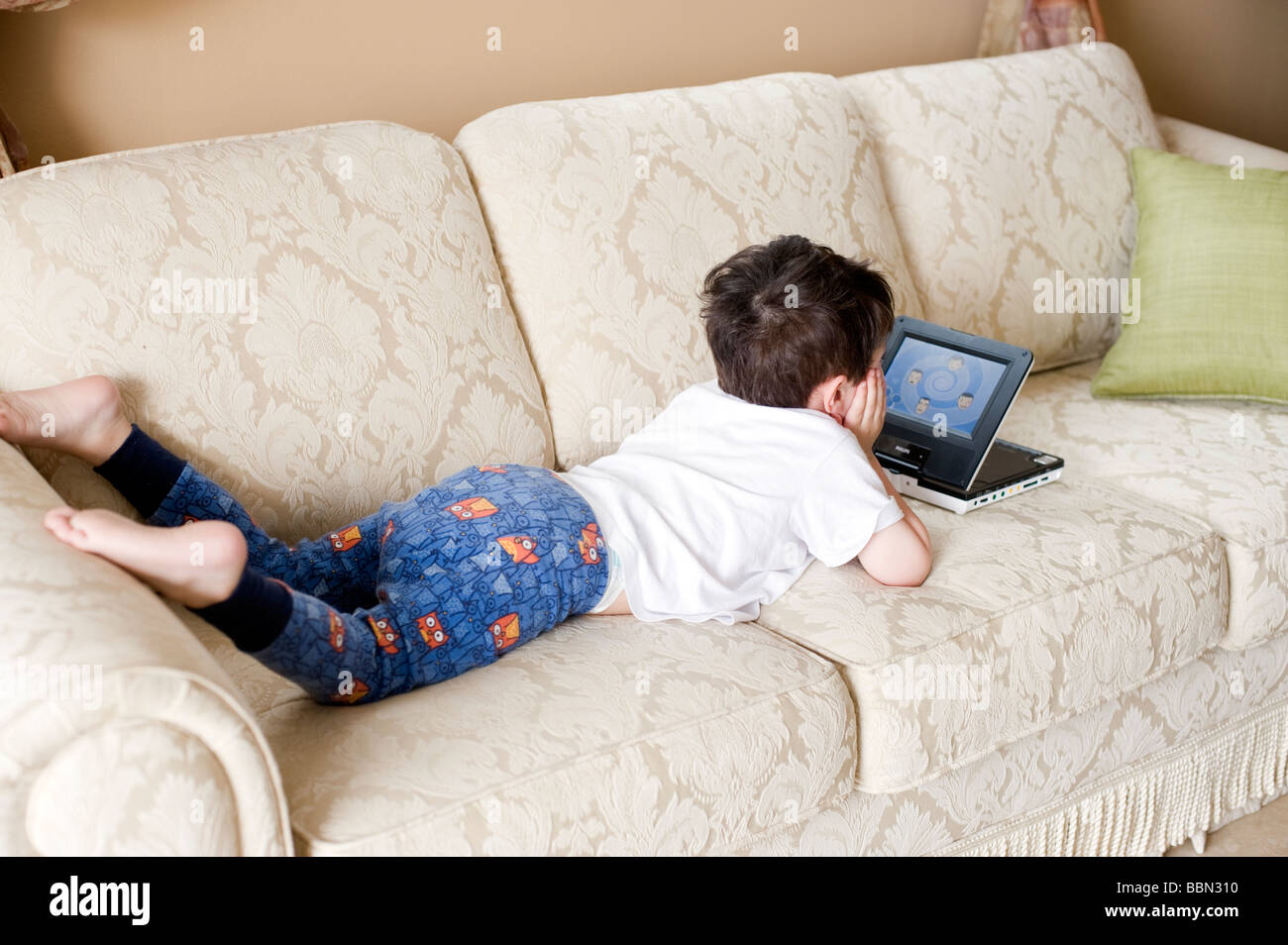 Three year old hispanic boy is mesmerized by a 'Wiggles' DVD playing on a portable DVD player Stock Photo