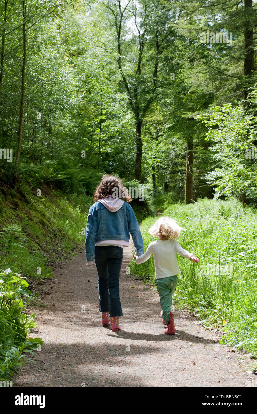 summer day - Two young girls walking along a woodland path on the Dolaucothi Estate National Trust Carmarthenshire West Wales UK Stock Photo