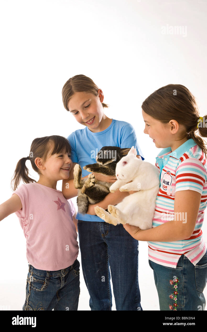 A group of three girls, the two older ones holding a rabbit in their arms Stock Photo