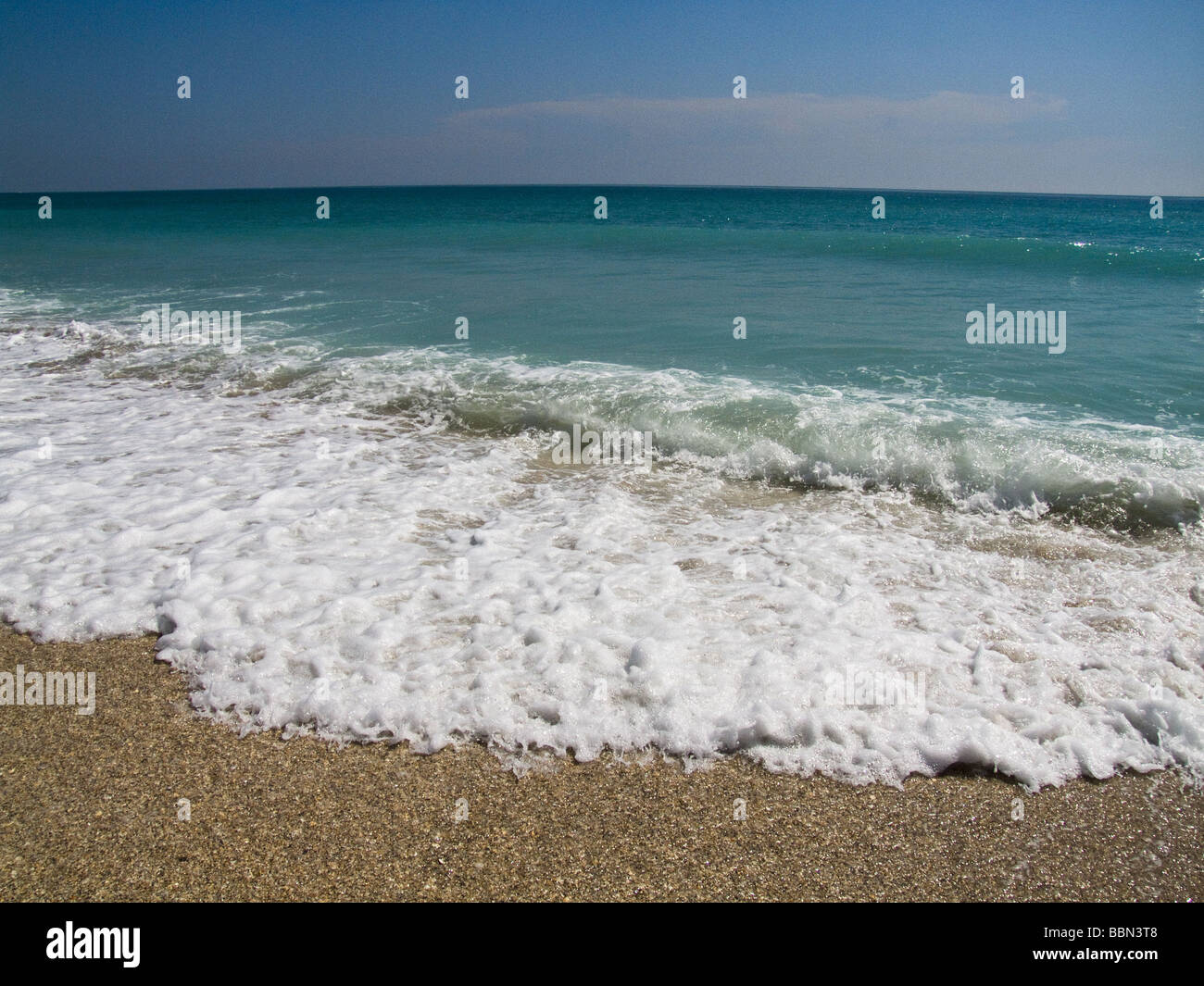 small waves wash up on shore at beach Stock Photo