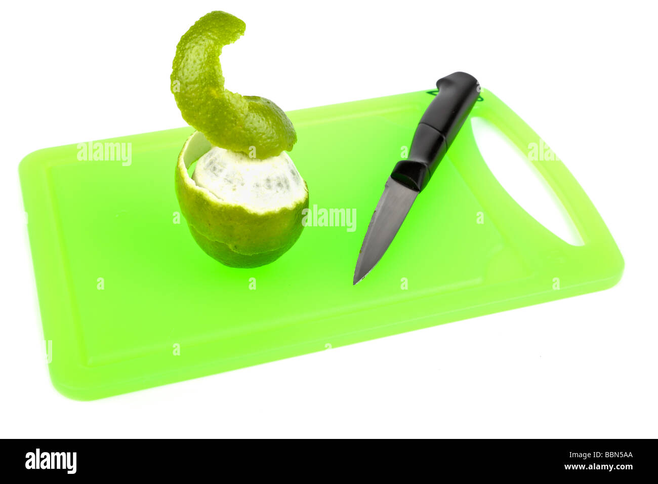 Lime being peeled with a knife on a cutting board Stock Photo
