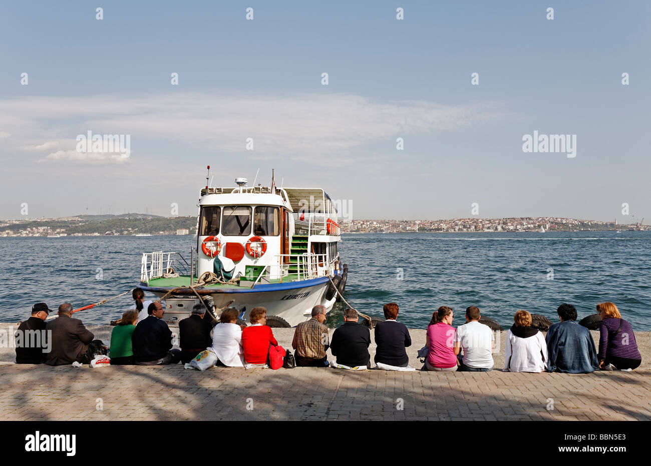 People sit in a row on the quay, waiting for the ferry, Bosphorus panorama, Kabatas, Istanbul, Turkey Stock Photo