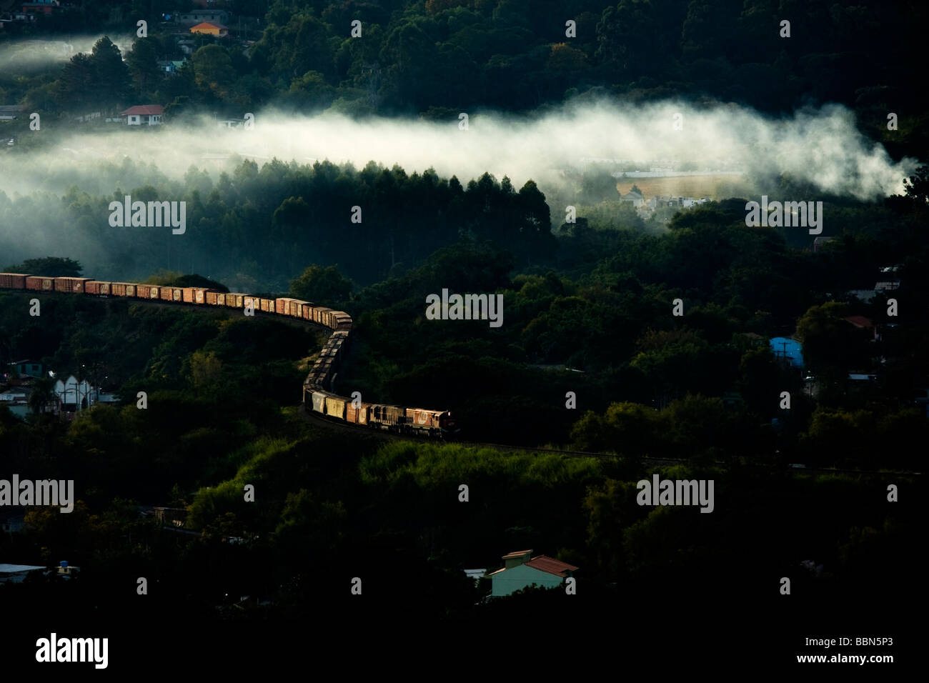 train going through a valley with smoke coming from houses on winter Stock Photo
