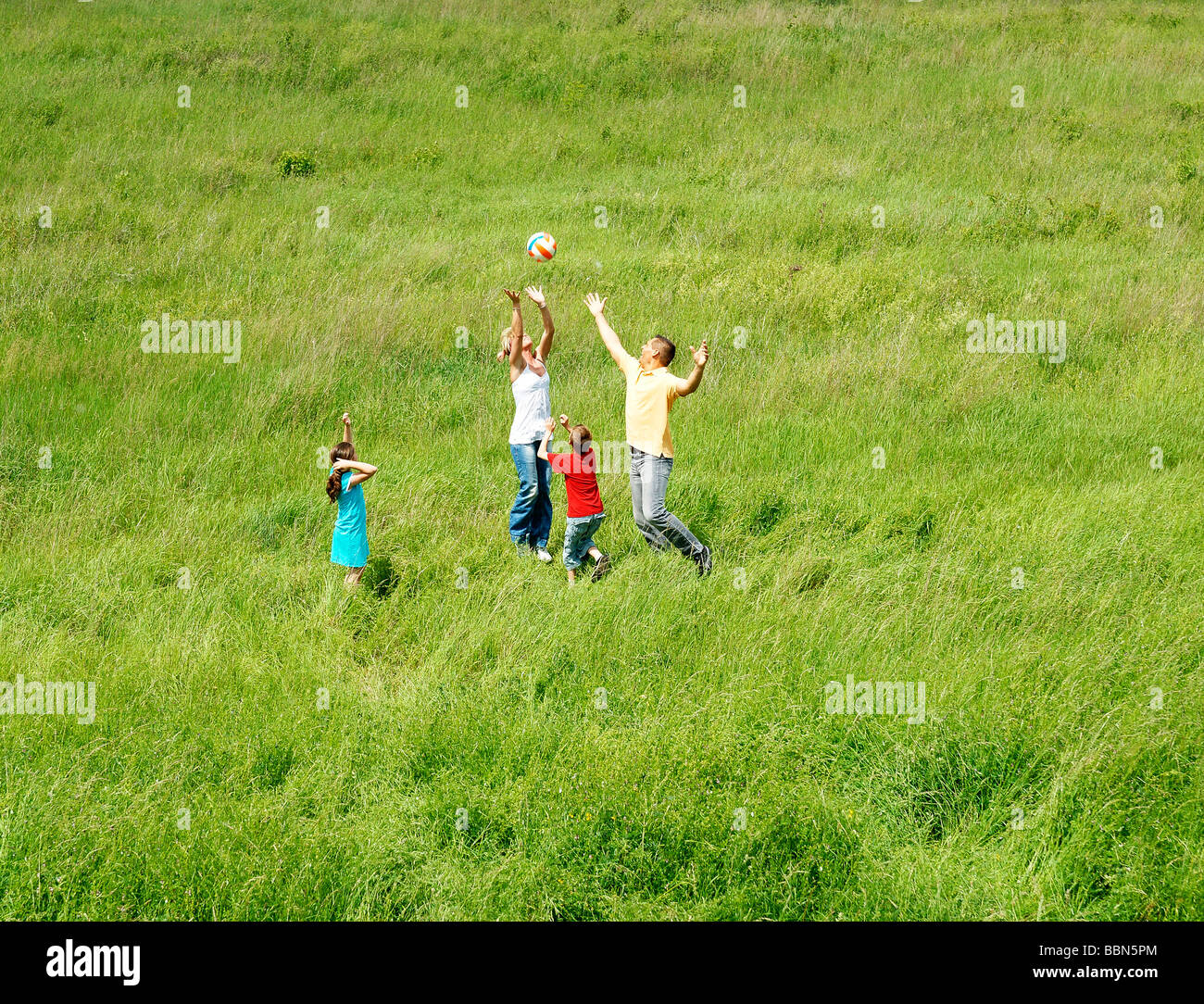 A family playing in a field with a ball Stock Photo