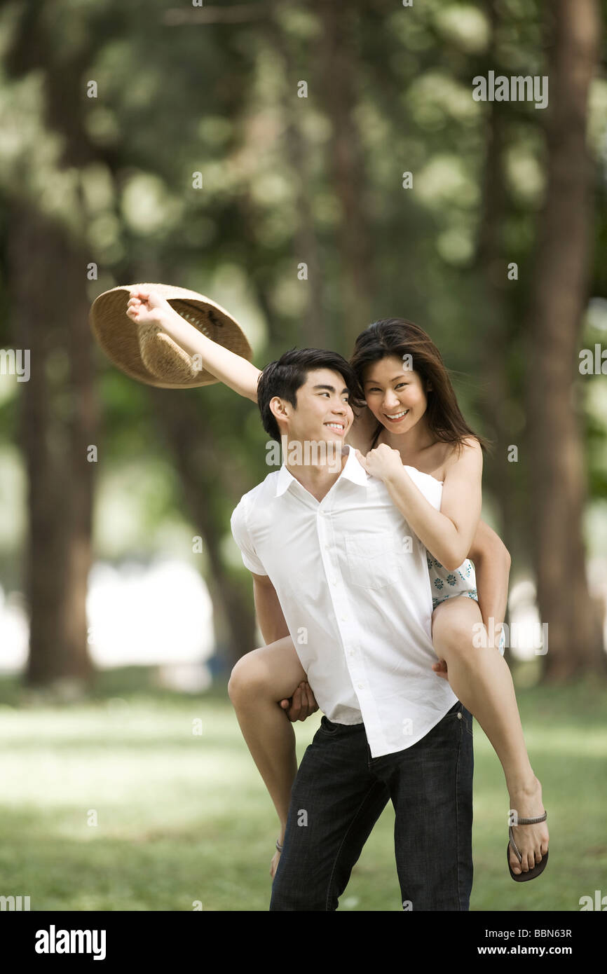 Man giving woman a piggyback in the park Stock Photo