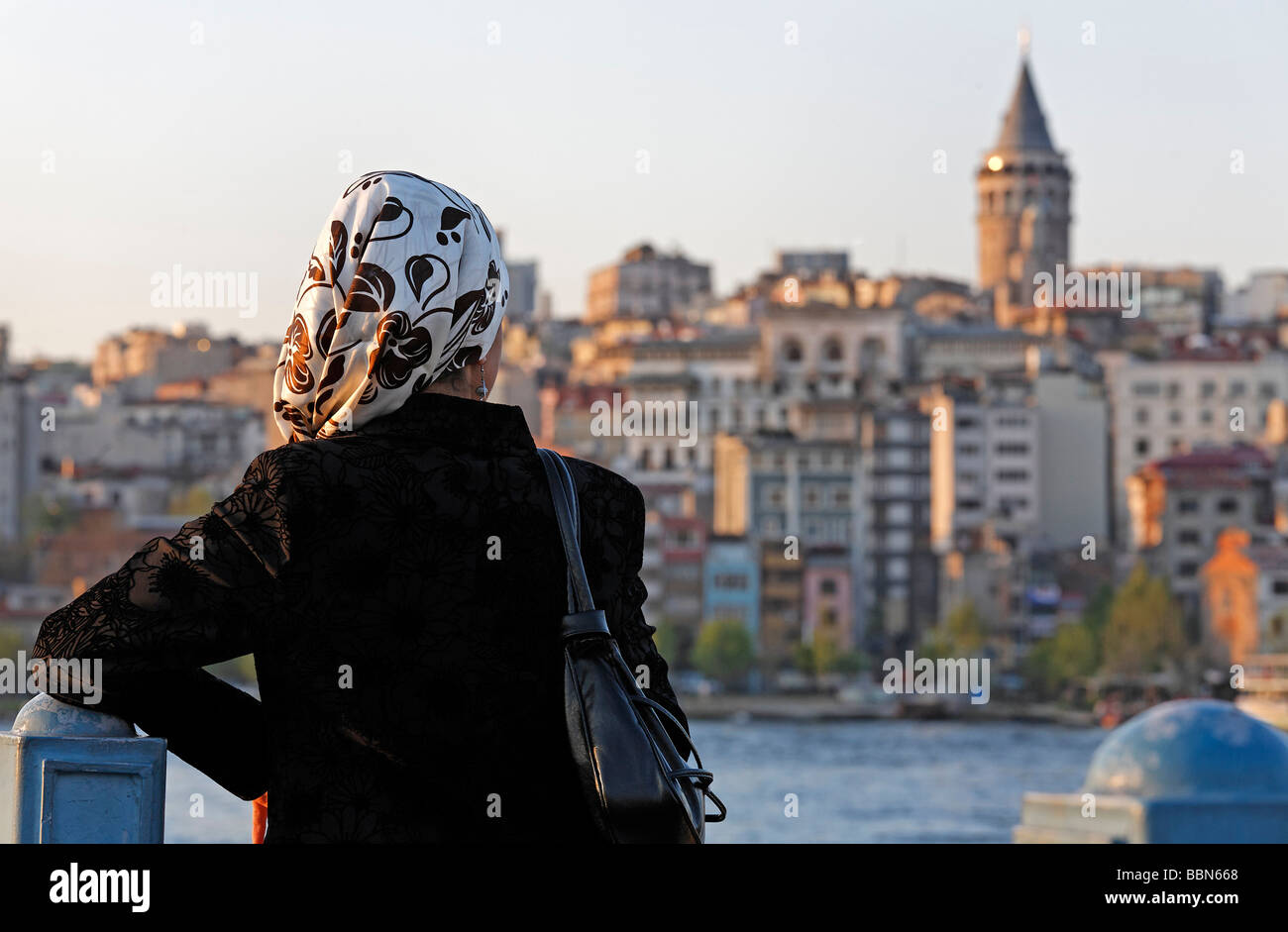 Young Muslim women with headscarf looks on the panorma of Beyoglu with the Galata Tower, Eminoenue, Istanbul, Turkey Stock Photo