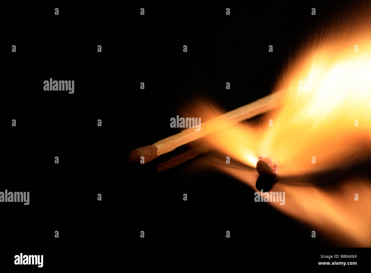 A match stick on fire, on a black reflective surface Stock Photo