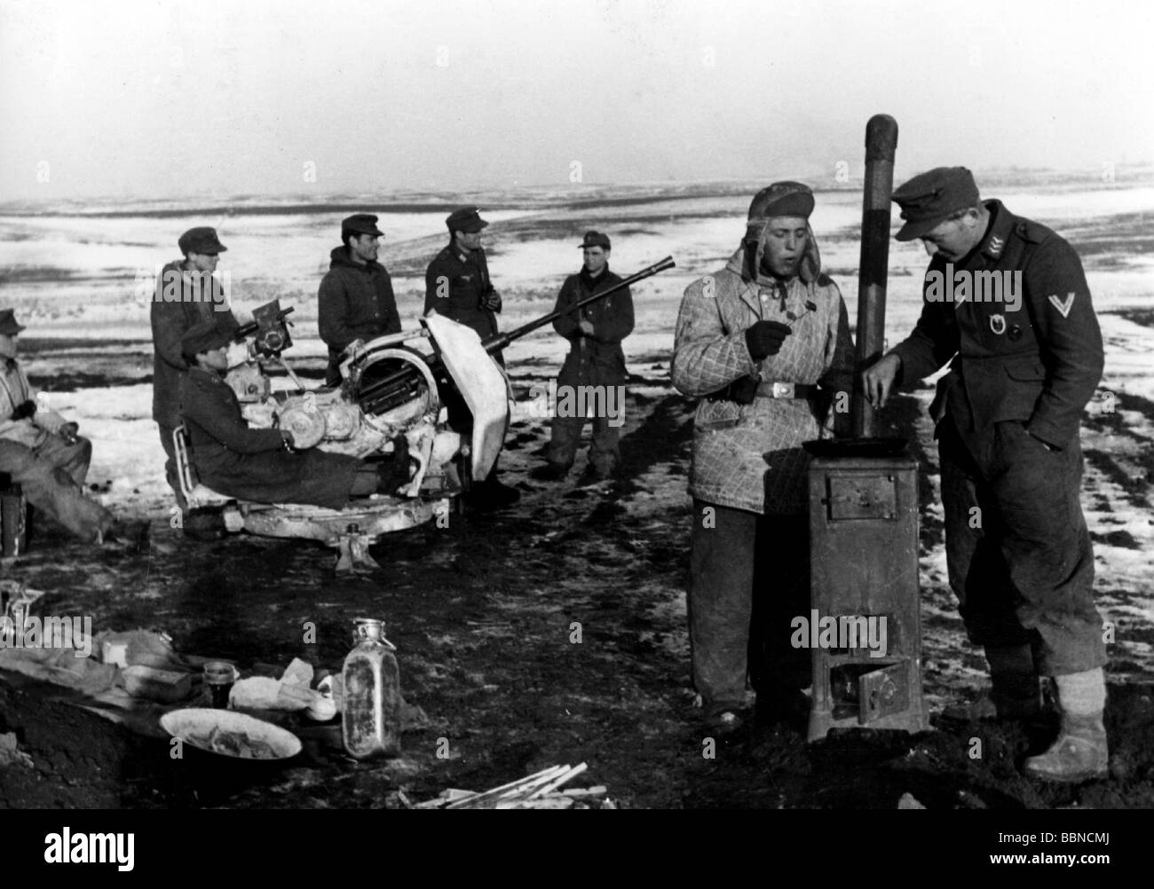 events, Second World War / WWII, Russia 1944 / 1945, German 20 mm anti-aircraft gun in firing position, in the forground a soldier peparing himself a meal on an iron stove, near Britskoye, Ukraine, 24.1.1944, Eastern Front, winter, Wehrmacht, snow, USSR, Luftwaffe, 2 cm Flak 38, soldiers, winter clothes, clothing, AA, 20th century, historic, historical, Soviet Union, Army Group South, eating, people, 1940s, Stock Photo