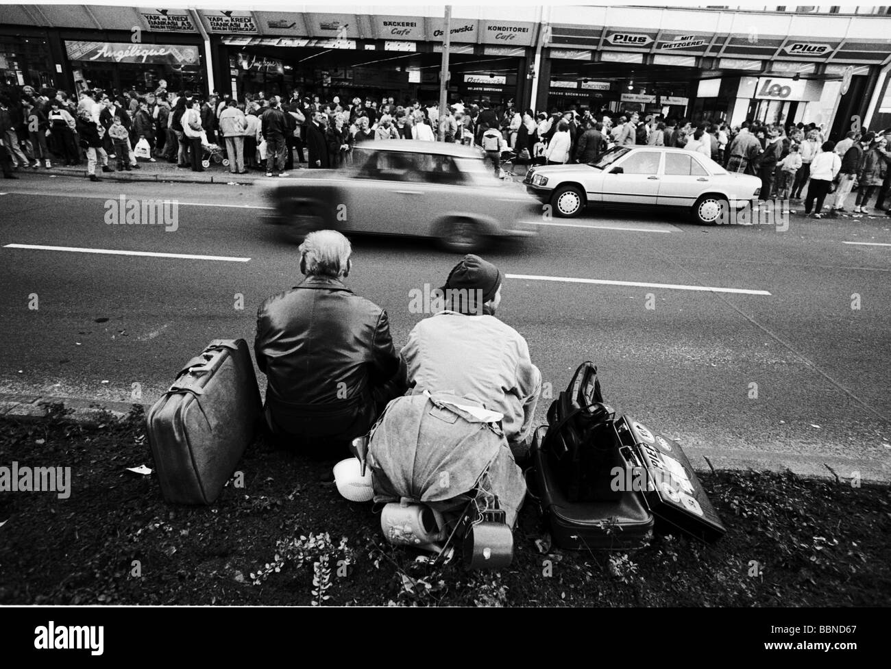 geography / travel, Germany, reunification, Berlin, people who left the GDR, sitting with luggage on roadside, West-Berlin, 11.11.1989, East Germany, historic, historical, East-Germany, West, Berlin Wall, fall, down, opening, freedom, crowd of people standing line up at shops, Trabant, car, street, 1980s, 80s, 20th century, leaving the country, November'89, November 89, men, man, male, woman, women, female, Stock Photo
