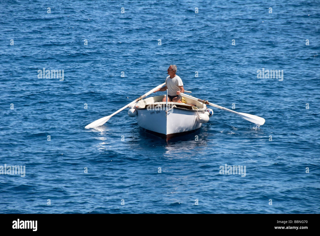 Man in a traditional gozzo or fishing boat on the Island of Giglio or Isola del Giglio off the Tuscan coast Stock Photo