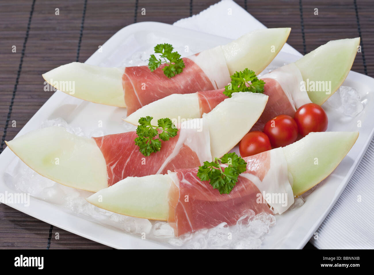 Melon slices with Parma ham on crushed ice Stock Photo