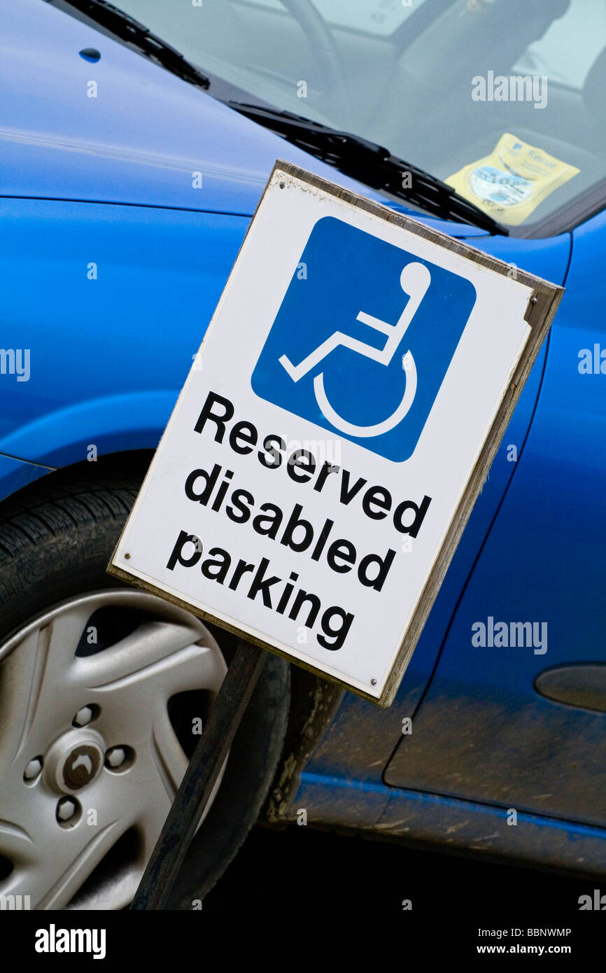 Reserved Disabled Parking sign next to blue car in car park Stock Photo