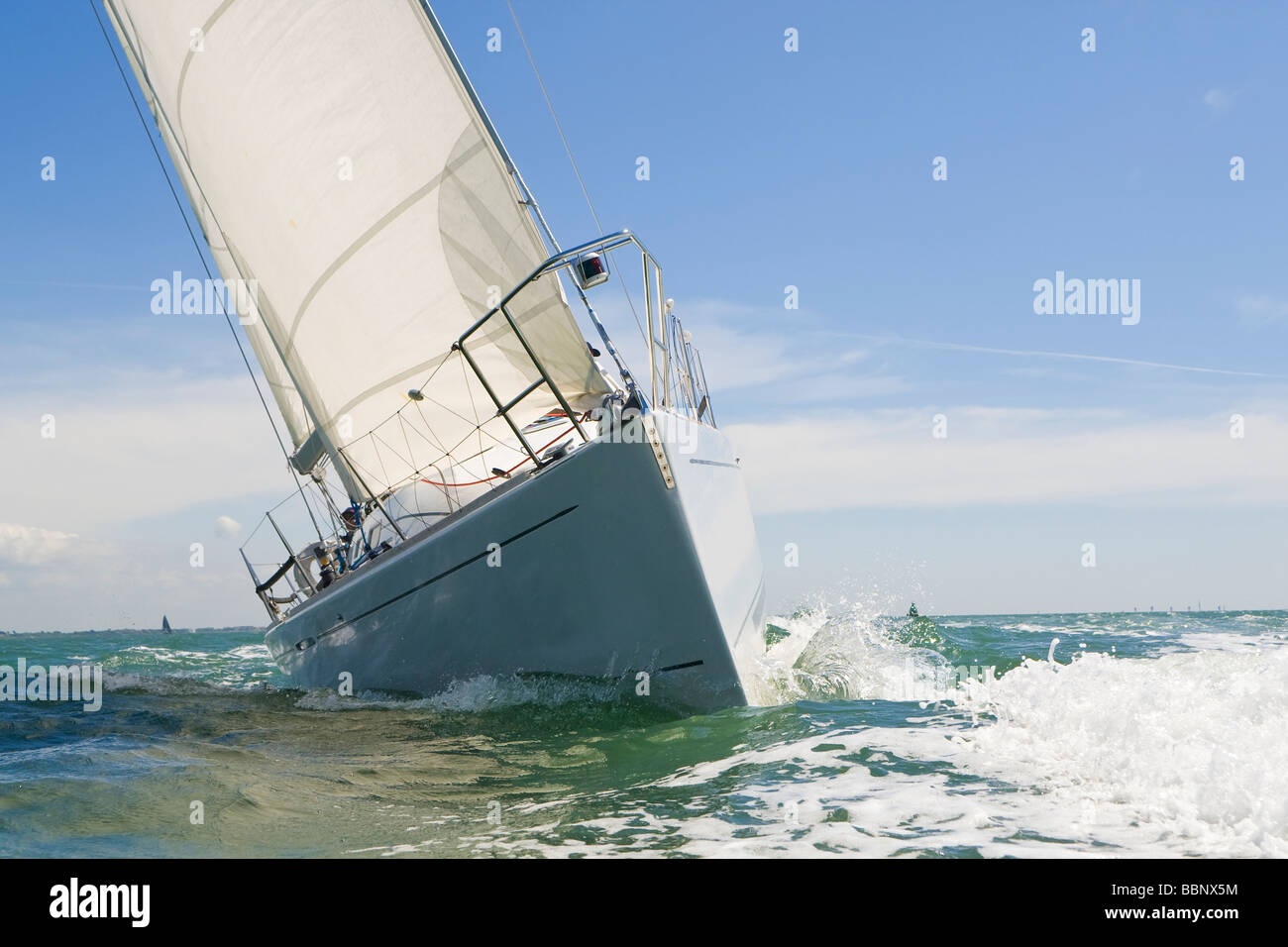 A beautiful white yachts racing close to the camera on a bright sunny day Stock Photo