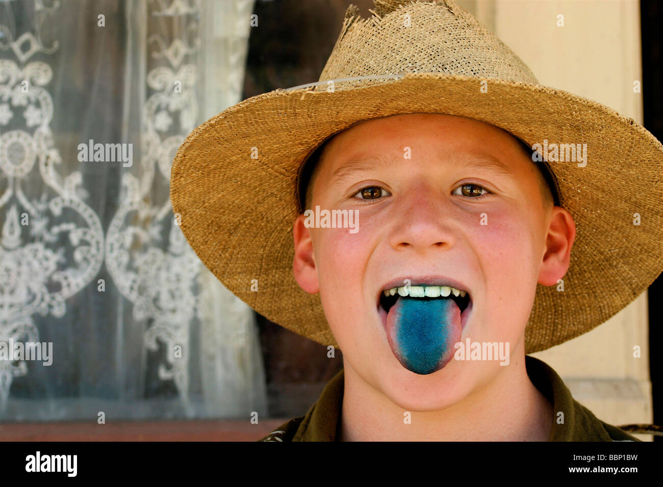 Blue tongued boy.  Freckle faced and adorable this all American boy sticks out his blue lollipop stained tongue for the camera. Stock Photo
