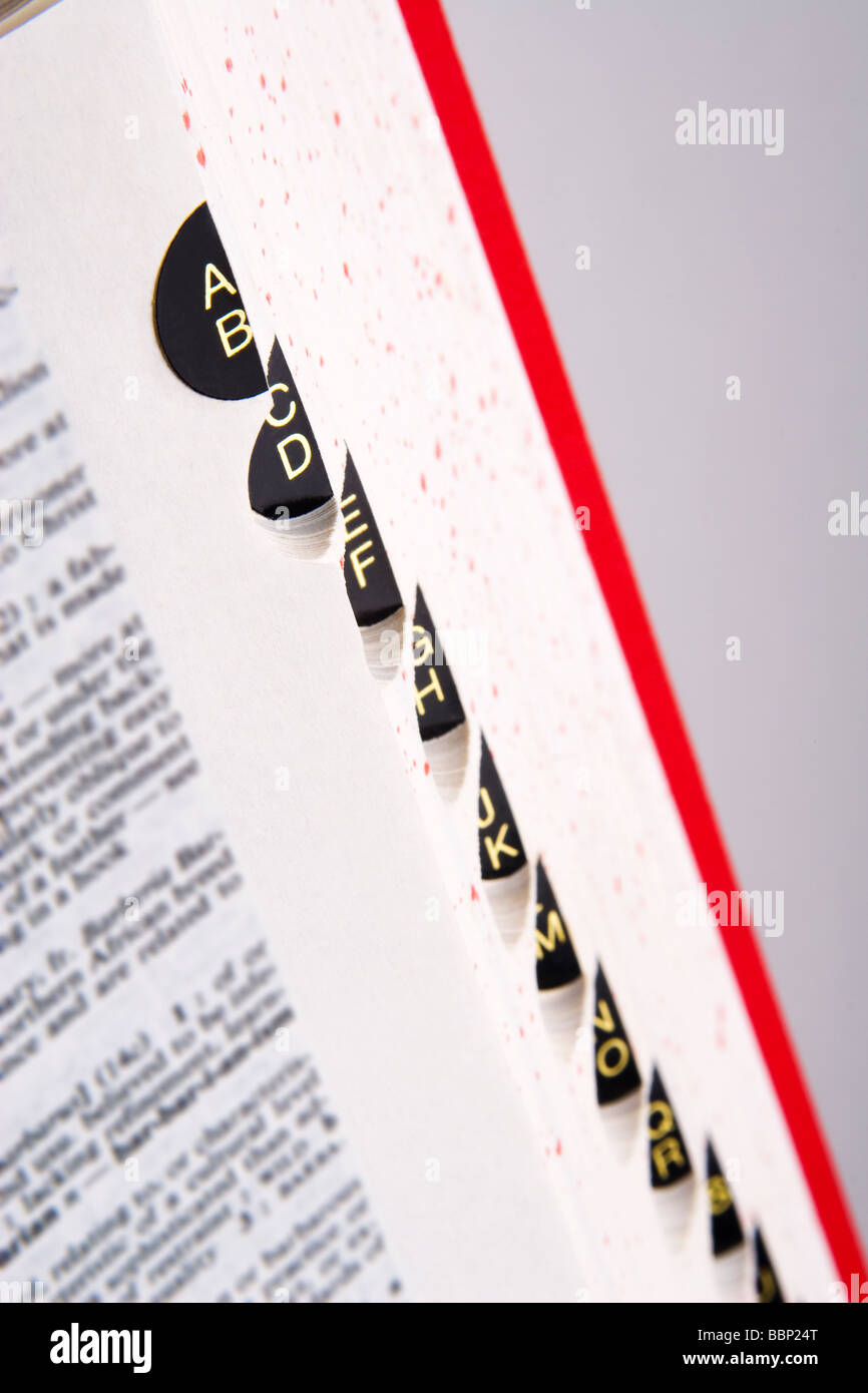 Close up of dictionary side with gold lettered tabs against grey background, selective focus Stock Photo