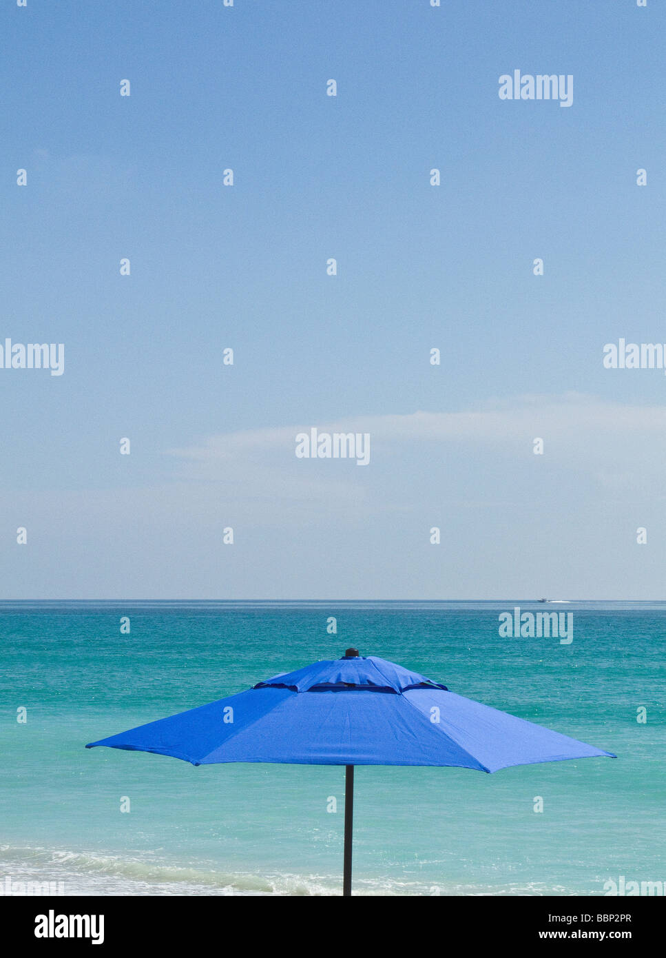 beach umbrella vacation summer ocean coastal Florida blue shade sun shelter water aqua sky protection under Stock Photo