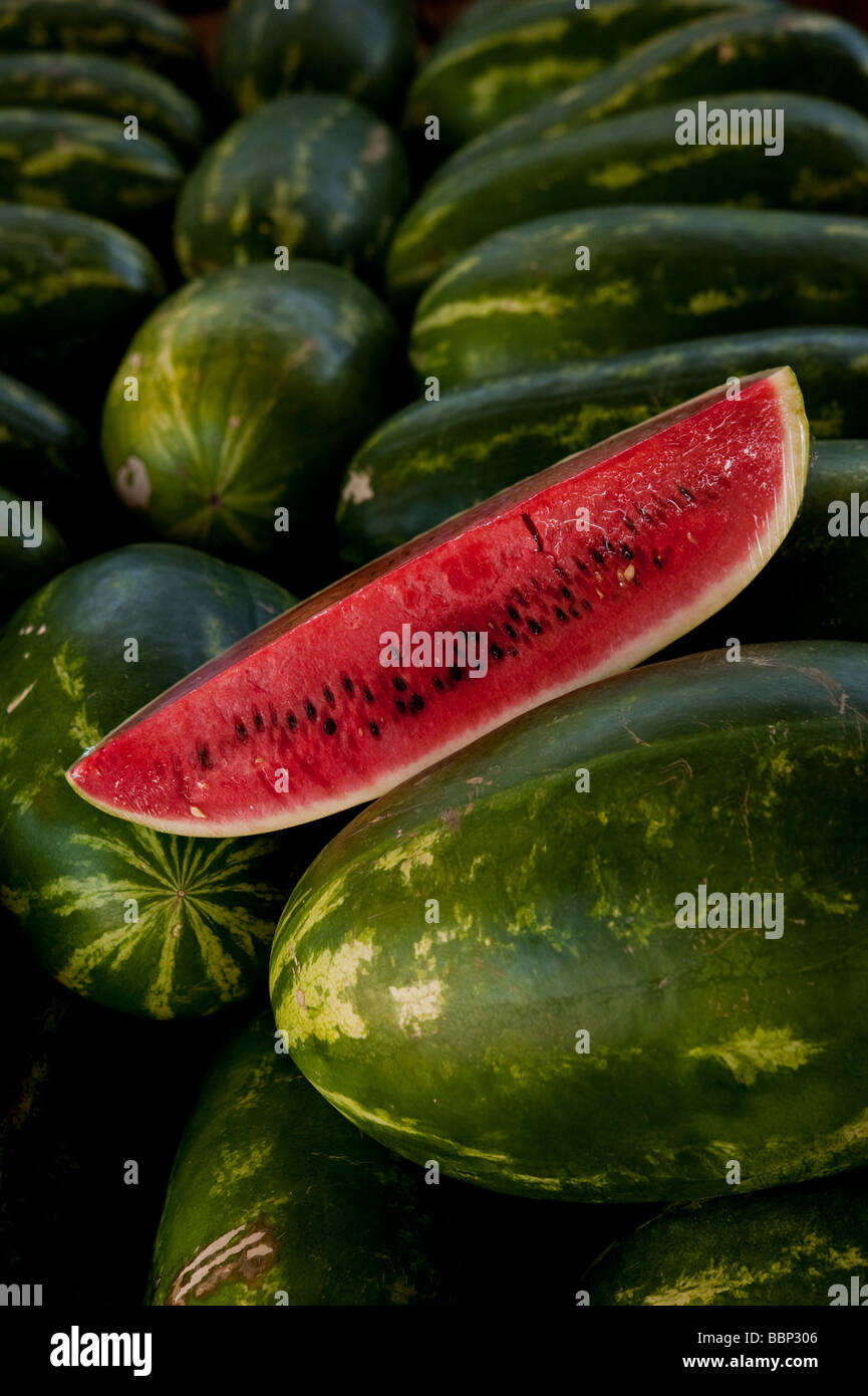 Image of a slice of watermelon on a bed of whole watermelons Stock