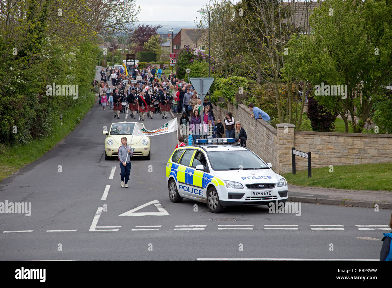 Police car heading Mayday procession on road May Day Woodmancote Cheltenham UK 2009 Stock Photo