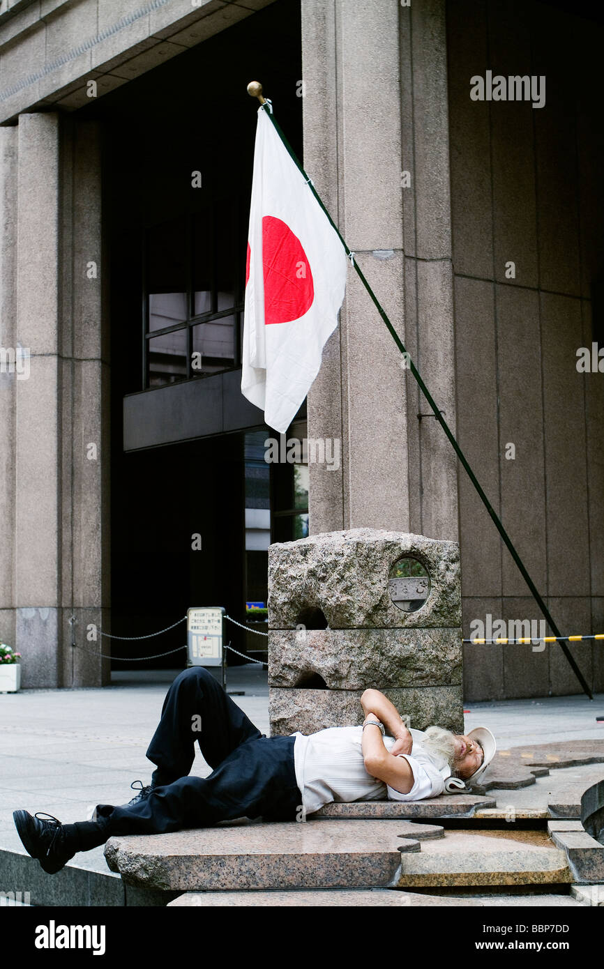 A Japanese man having a nap under the national flag. Stock Photo