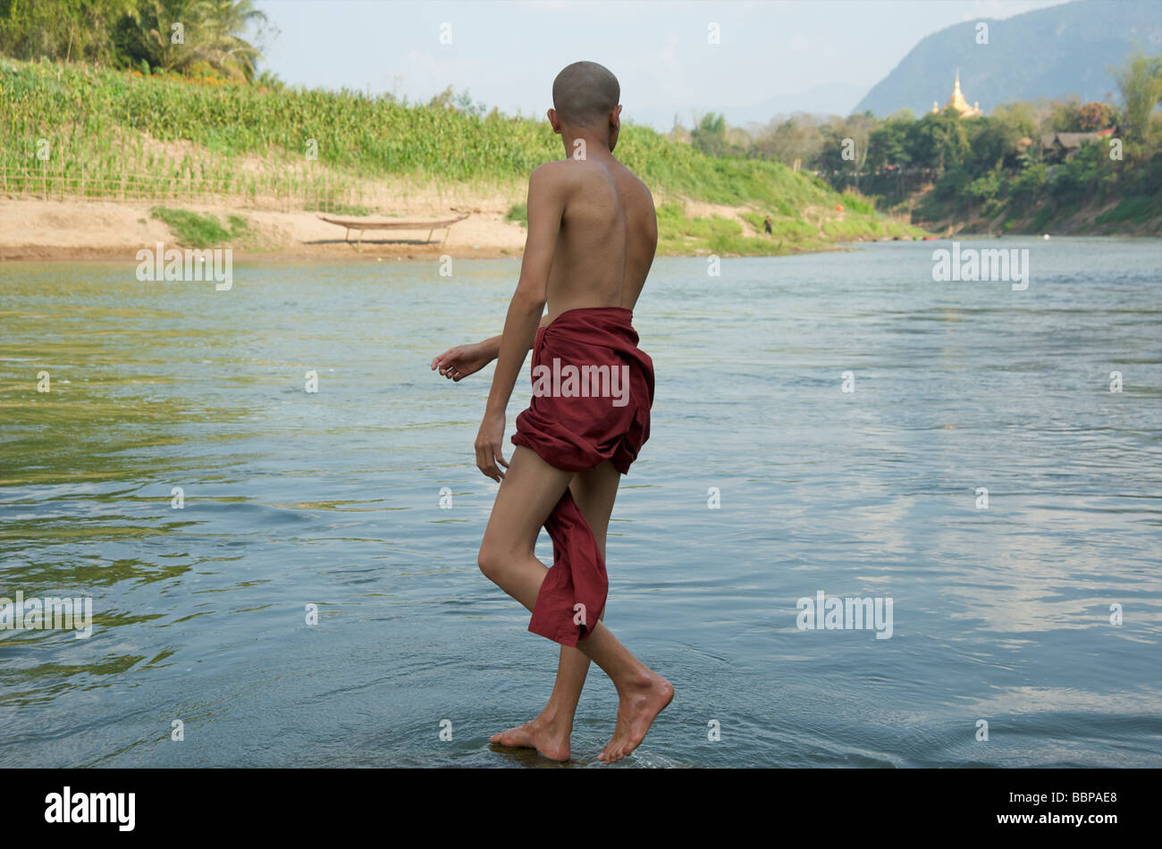 A young Buddhist monk about to dive into the Nam Khan river in Luang Prabang Laos Stock Photo