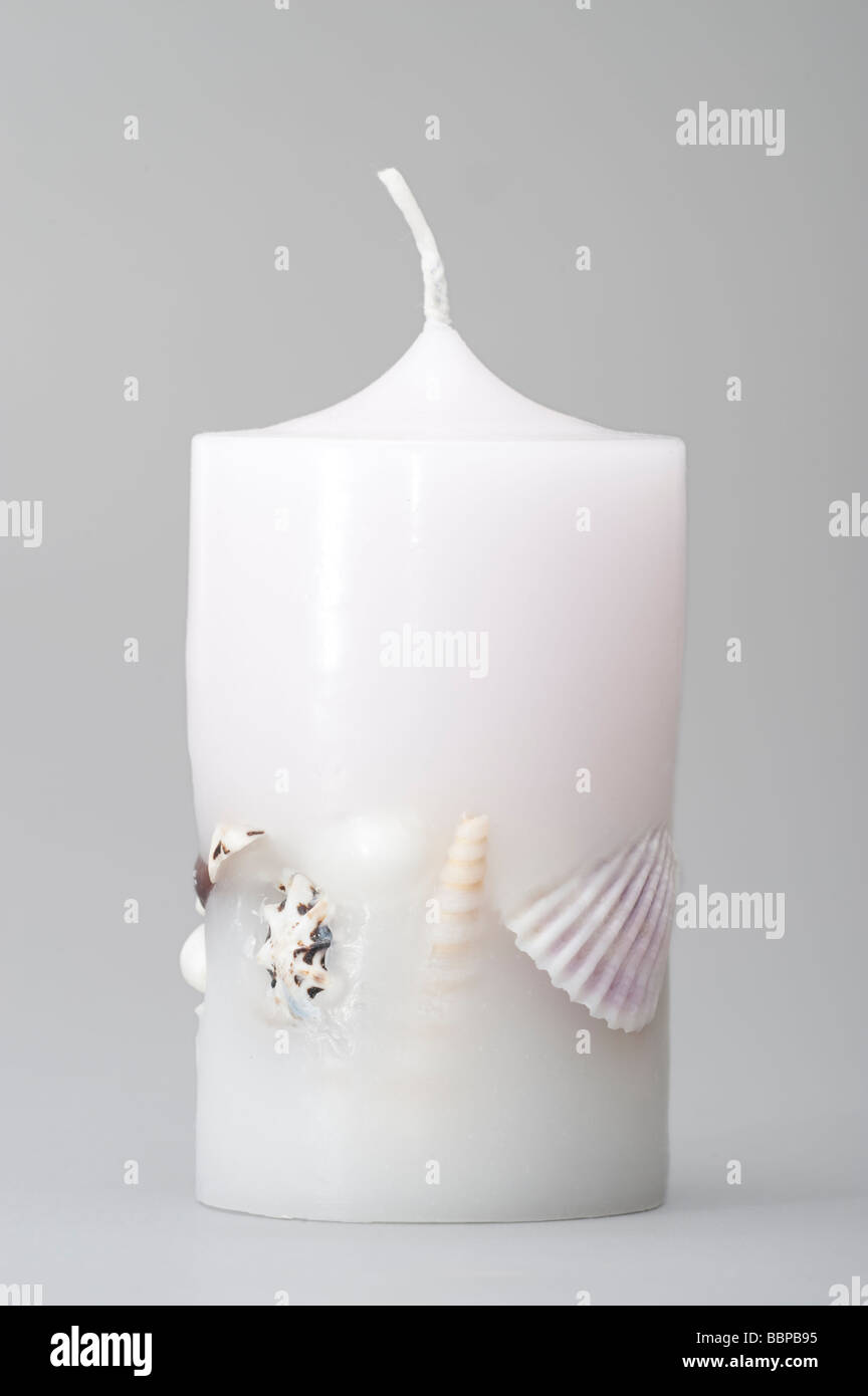 White wax candle with embedded sea shells Stock Photo