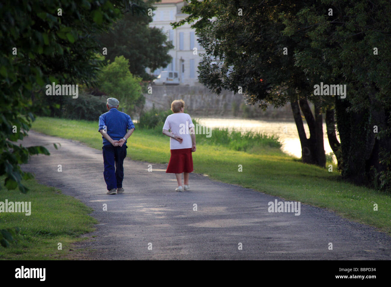 retired elderly couple take a stroll along the river banks at dusk in Charente area of France. Stock Photo
