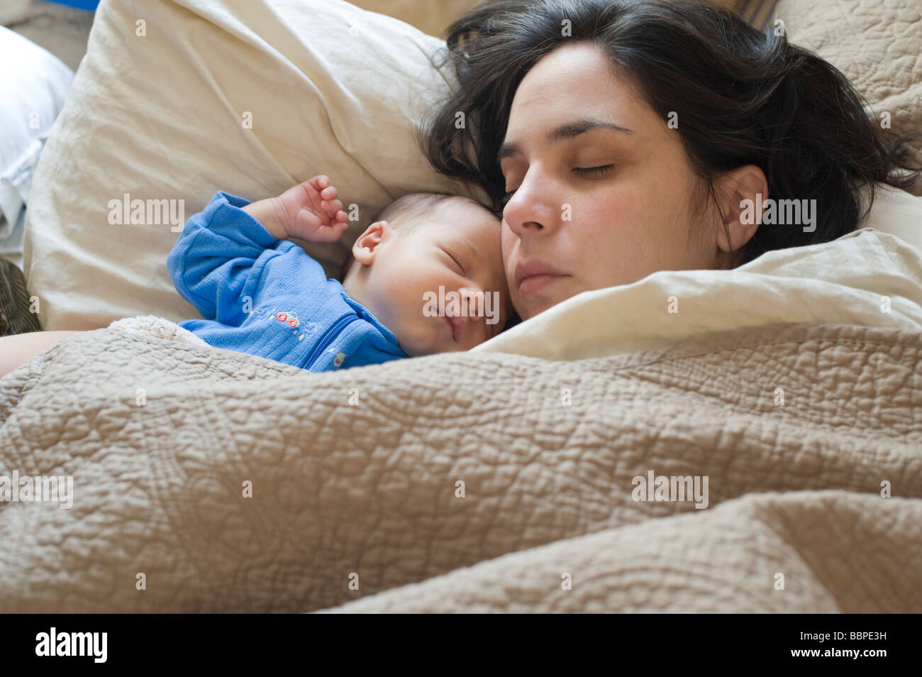 Thirty-five year old Puerto Rican woman lays in bed with her one month old baby boy Stock Photo