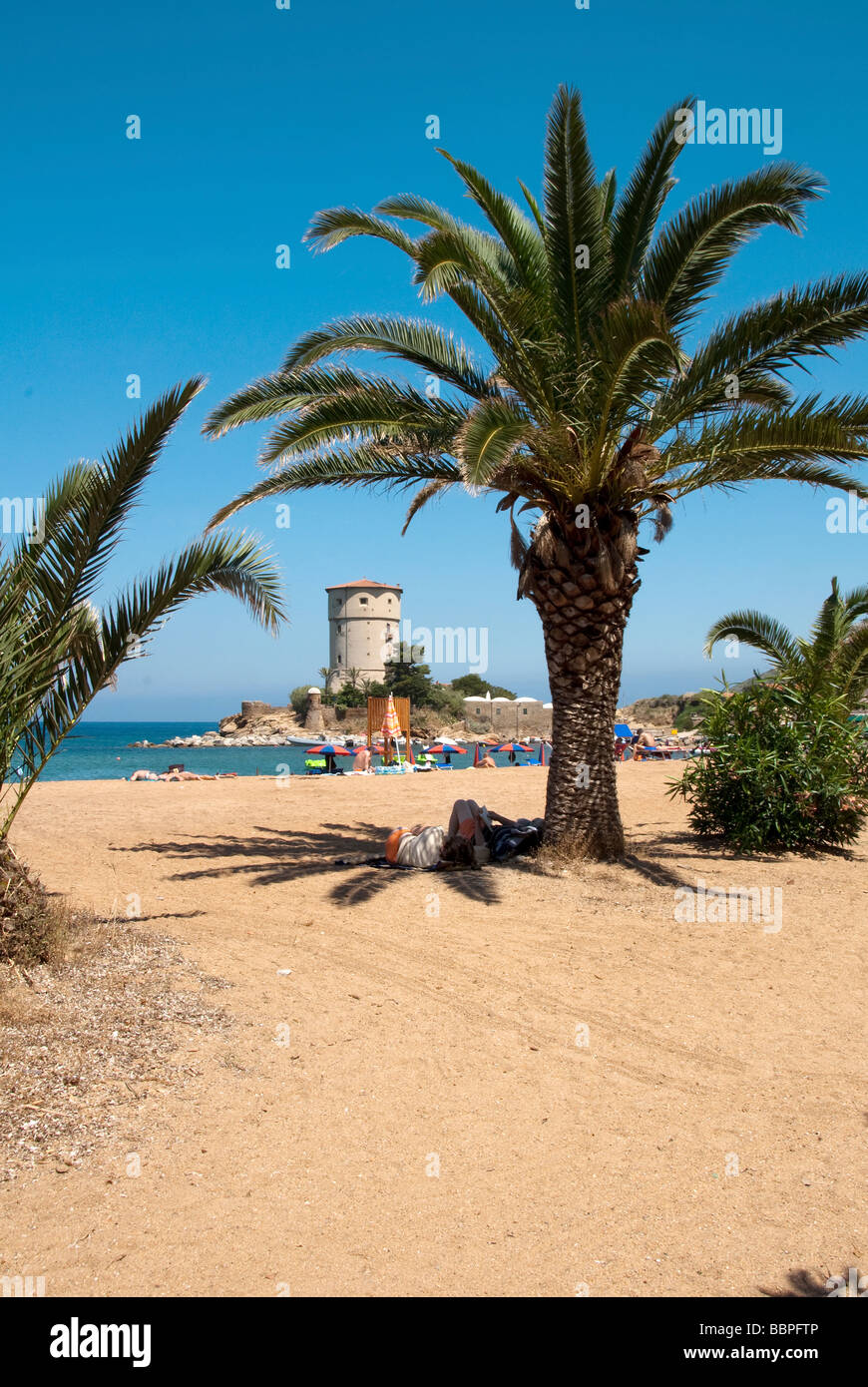 A couple laze reading books in the shade of palm tree at Giglio Campese the beach on the Island of Giglio or Isola del Giglio Stock Photo