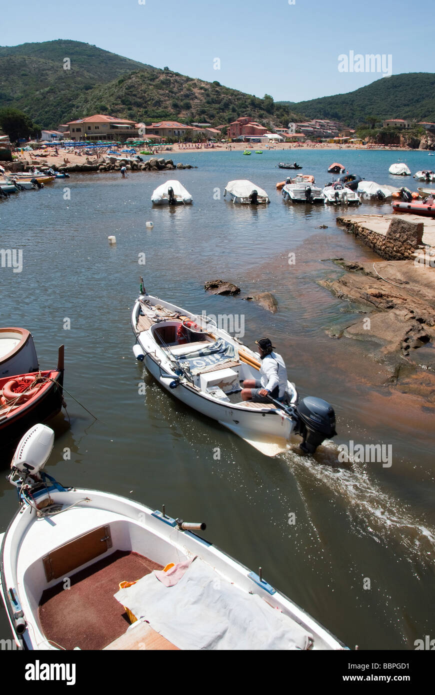 A man navigates his 'gozzo', a small boat through a rocky channel, Island of Giglio or Isola del Giglio Stock Photo