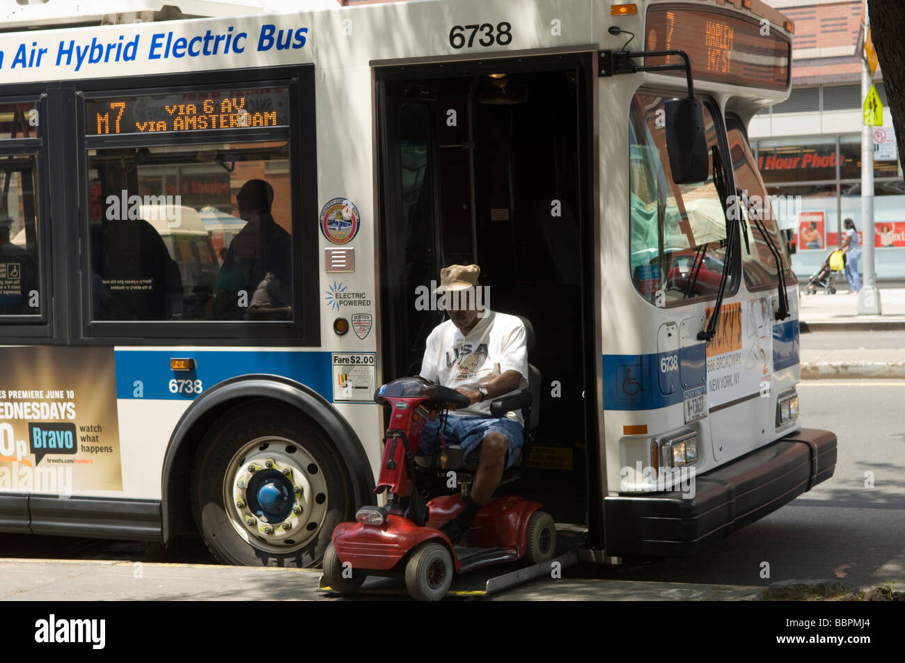 A man on a scooter uses a lift to board a MTA bus in Harlem in New York