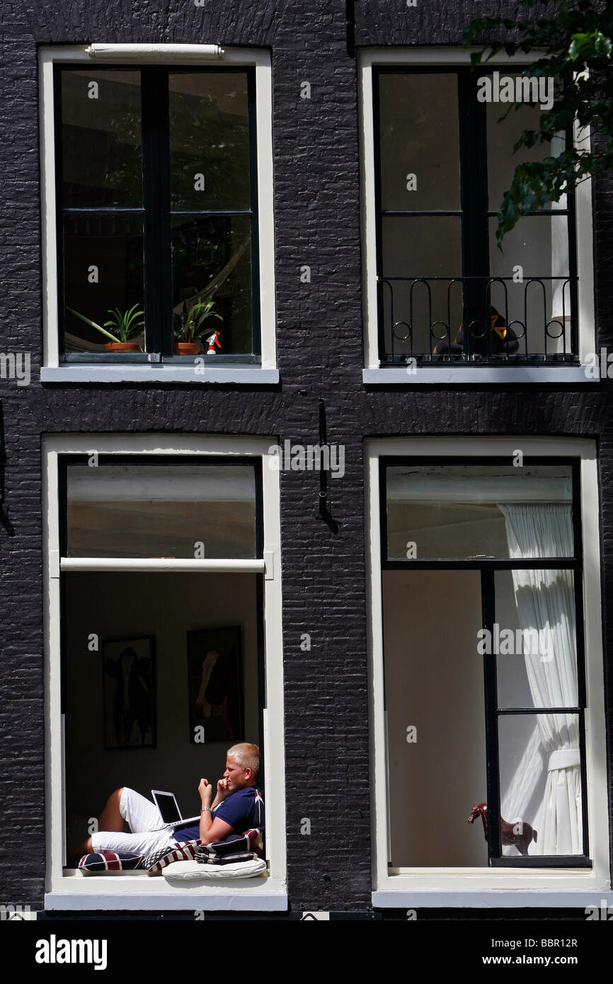 MAN AT THE WINDOW WITH HIS LAPTOP AND MOBILE PHONE, TRADITIONAL DUTCH  HOUSES, AMSTERDAM, NETHERLANDS, HOLLAND Stock Photo - Alamy