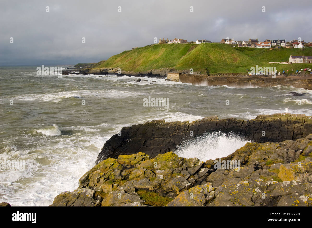 Stormy waves at the traditional fishing village and harbour of Collieston, Scotland. The rocks are of granite. Stock Photo
