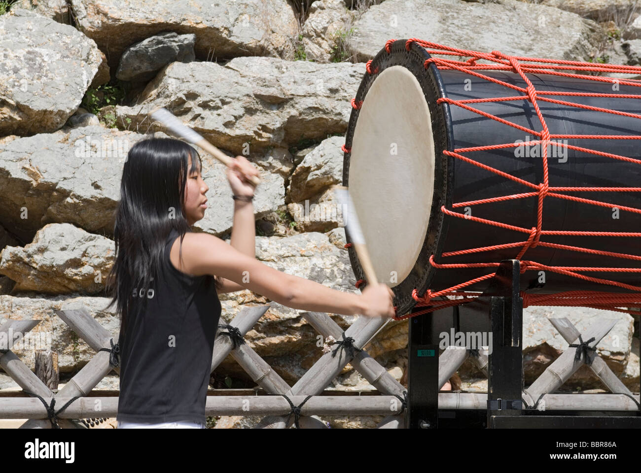 A teenage girl drummer troupe pounds out rhythms on traditional Japanese taiko drums Stock Photo