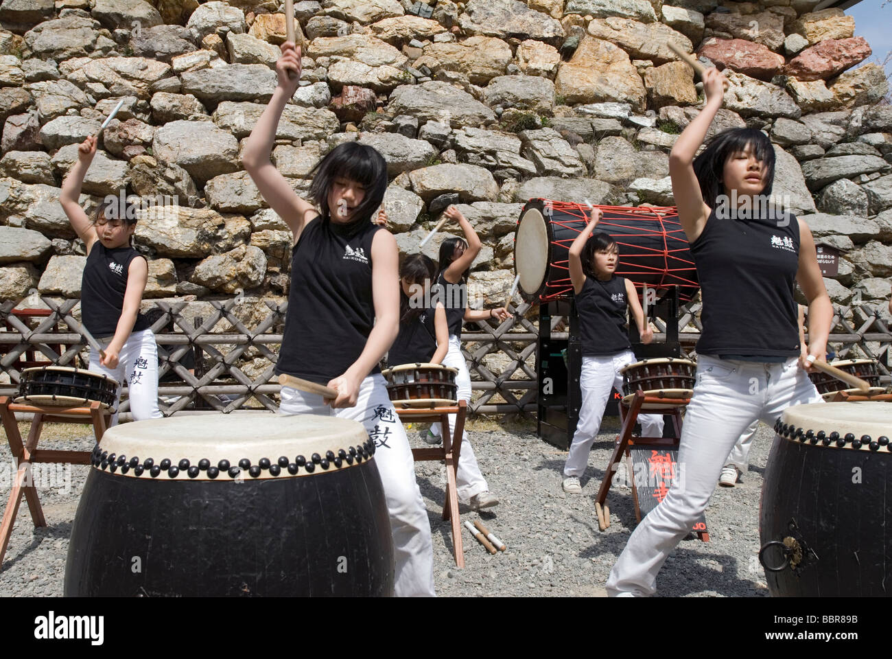 A teenage girl drummer troupe pounds out rhythms on traditional Japanese taiko drums Stock Photo