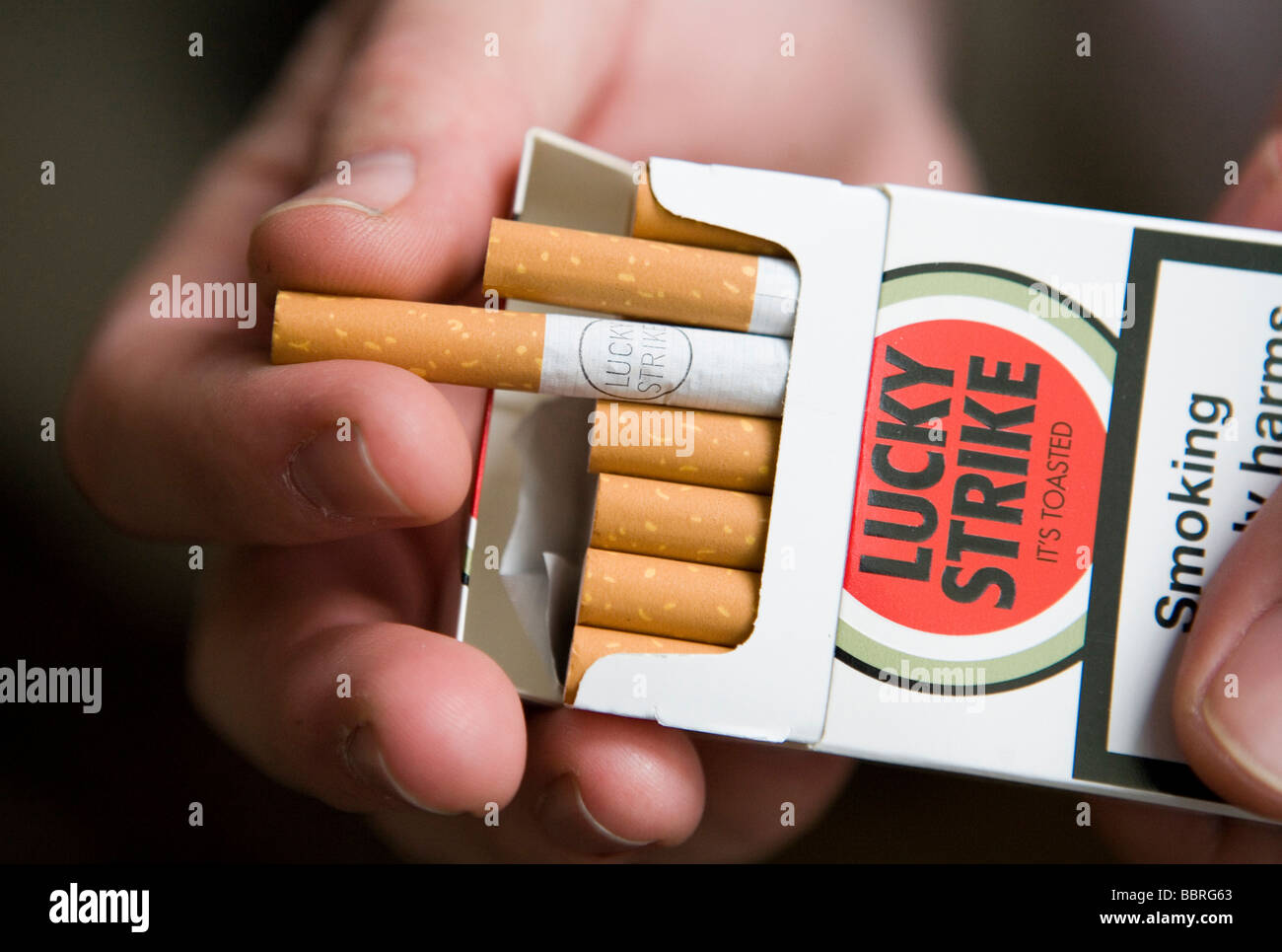 A smoker takes a Lucky Strike cigarette made by British American Tobacco from a packet Stock Photo